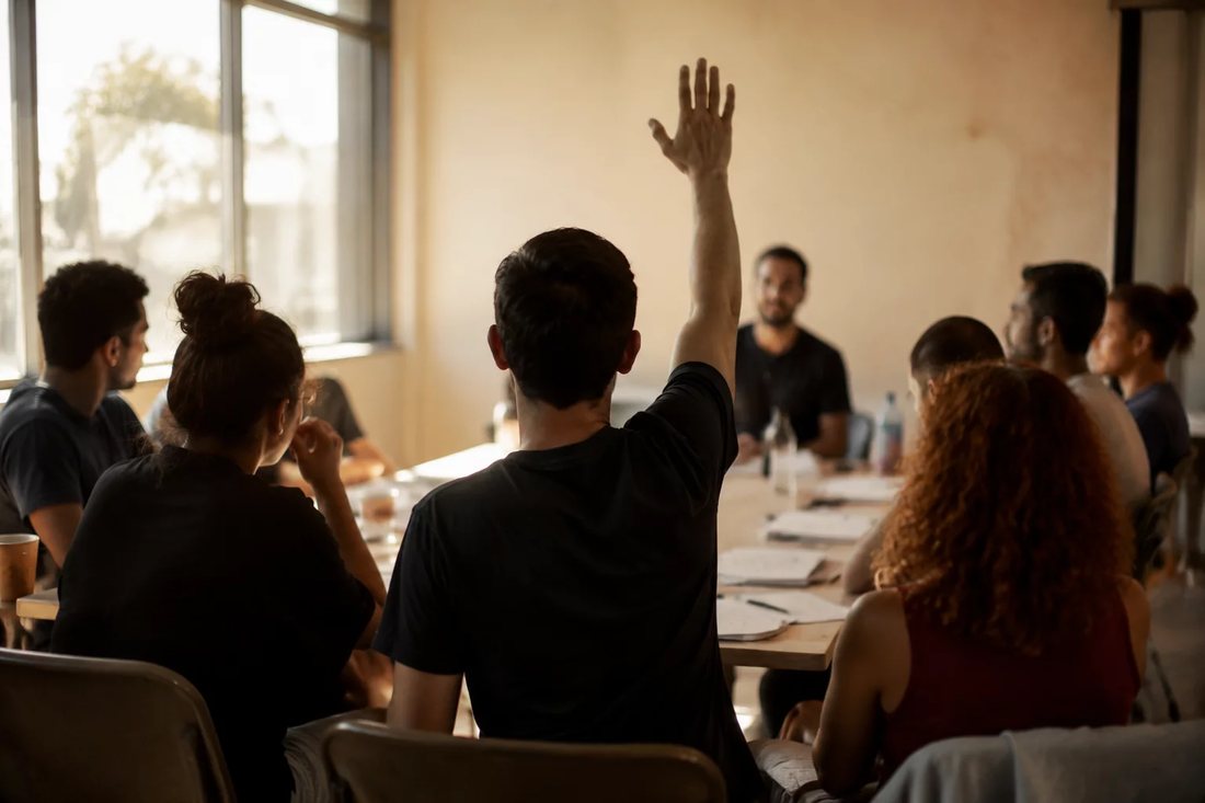 Pessoas numa sala de reunião clara, uma delas de pé explicando um ponto